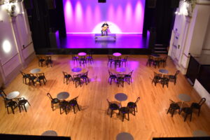 Socially distanced tables laid out in front of the Derby Hall stage at The Met