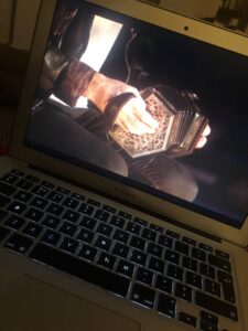 Close-up shot of an accordian being played visible on a laptop screen.