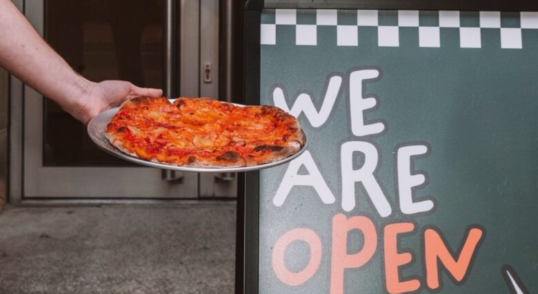 A pizza held near the entrance sign at Fratelli's.